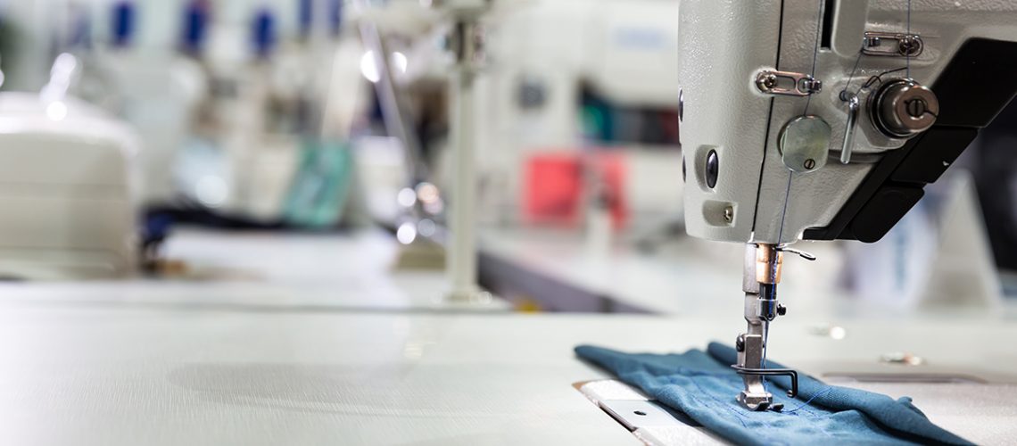 Sewing machine on textile fabric closeup, nobody. Factory production, sew manufacturing, overlock